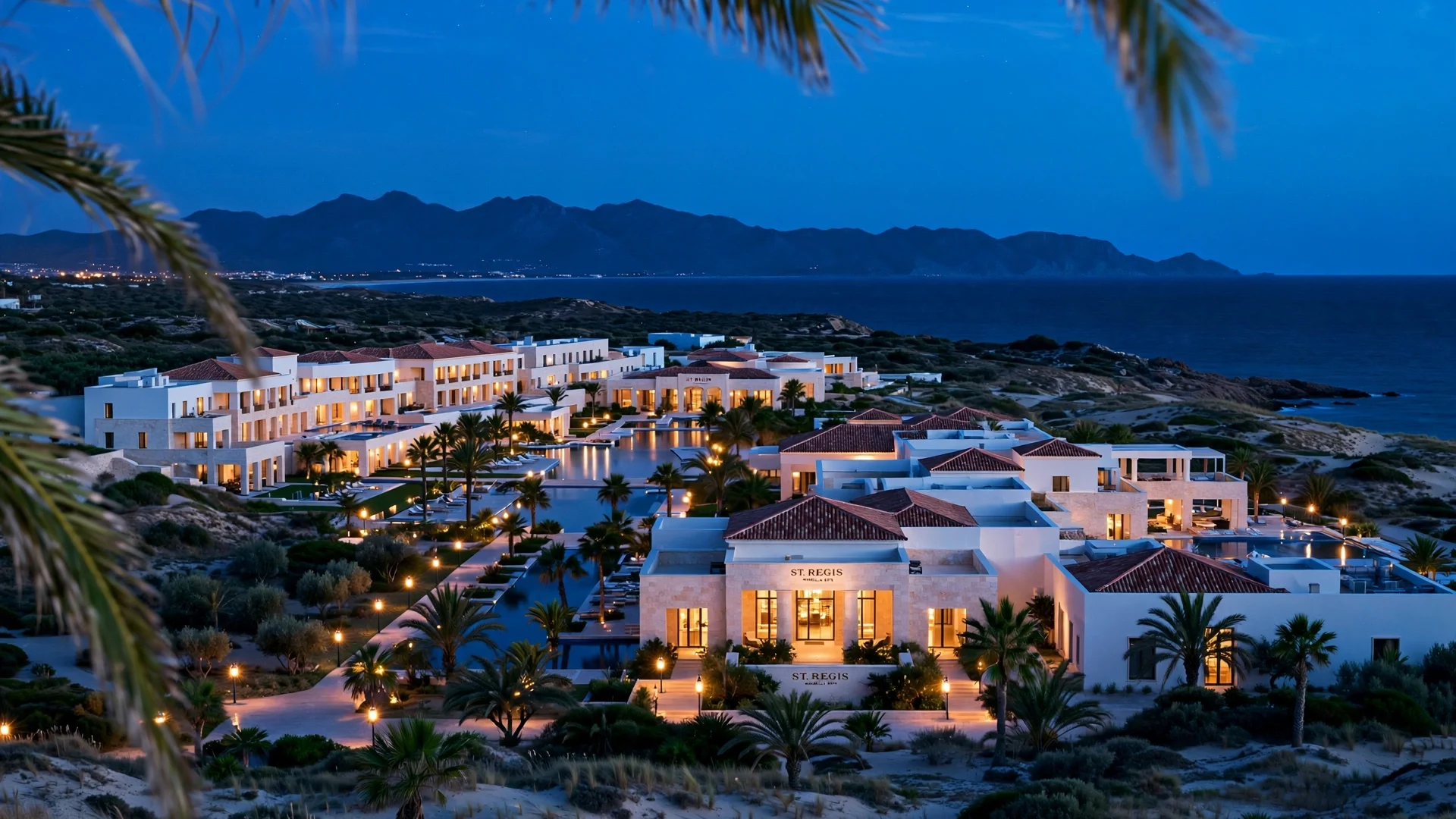 Complejo hotelero de lujo iluminado al anochecer junto al mar en Marbella, con piscinas y palmeras